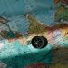 A compass placed on a detailed world map with colored push pins.